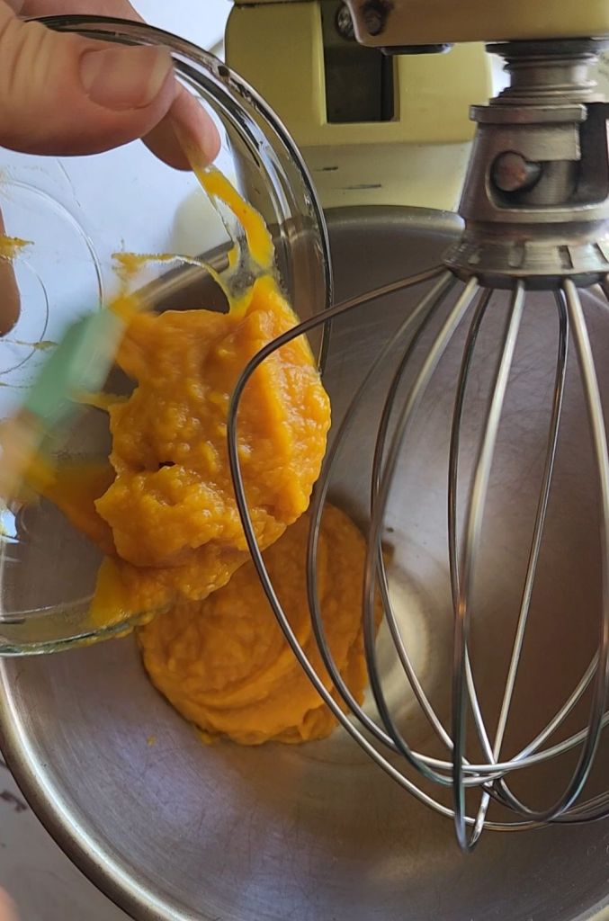 Adding pumpkin Puree to the mixing bowl to make The best dairy free low carb chocolate cake recipe.