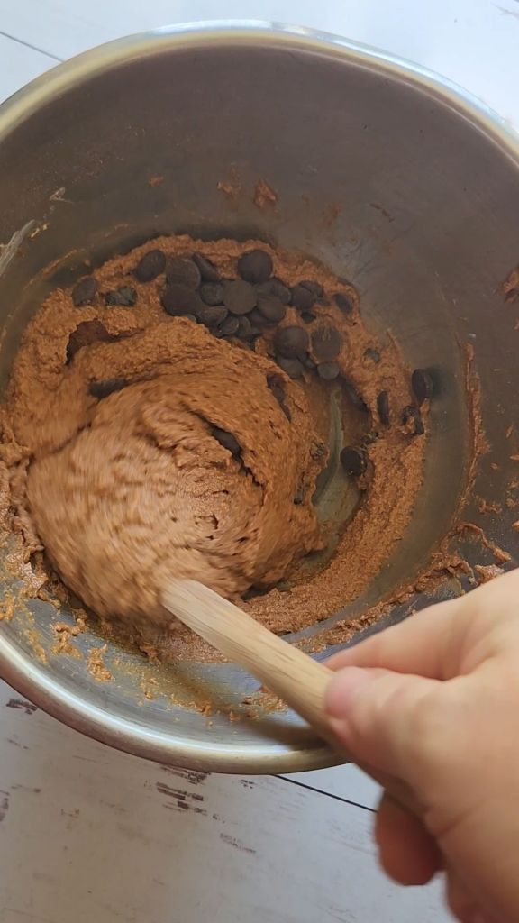 Folding chocolate chips into the batter of The best dairy free low carb chocolate cake recipe.