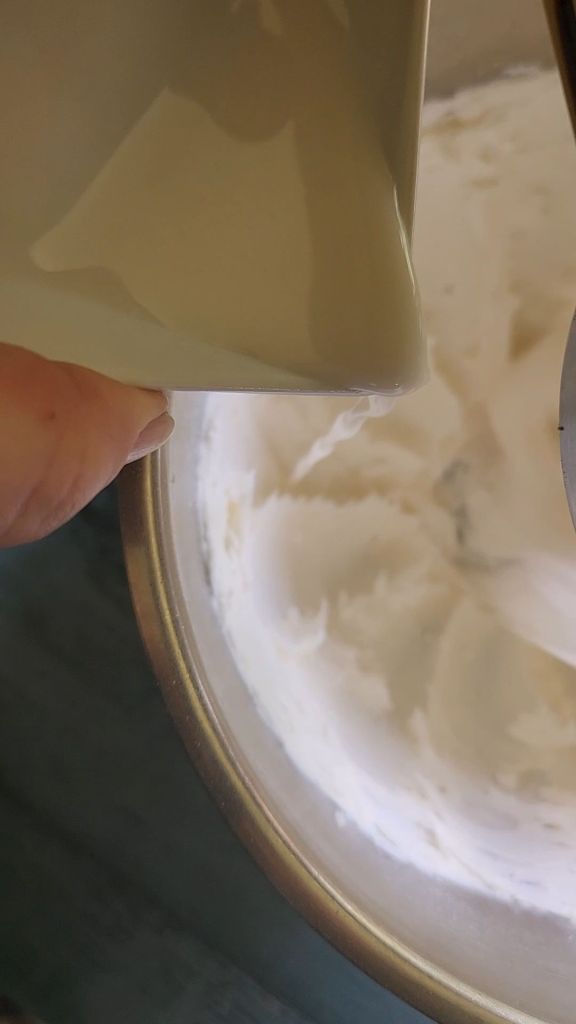 Adding almond milk to mixer making easy dairy-free low carb buttercream frosting recipe.