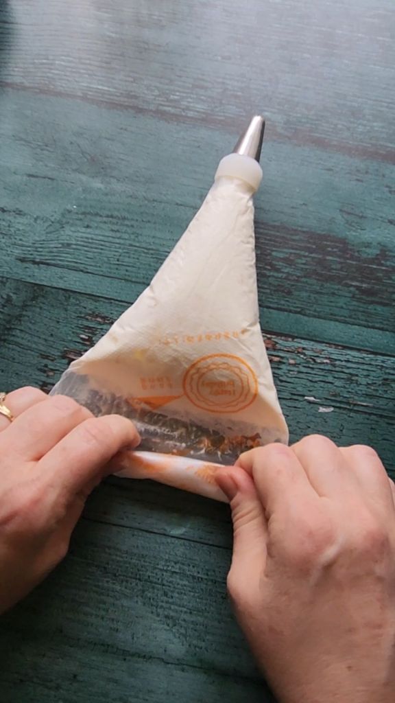 Prepping the frosting piping bag to pipe easy dairy-free low carb buttercream frosting.