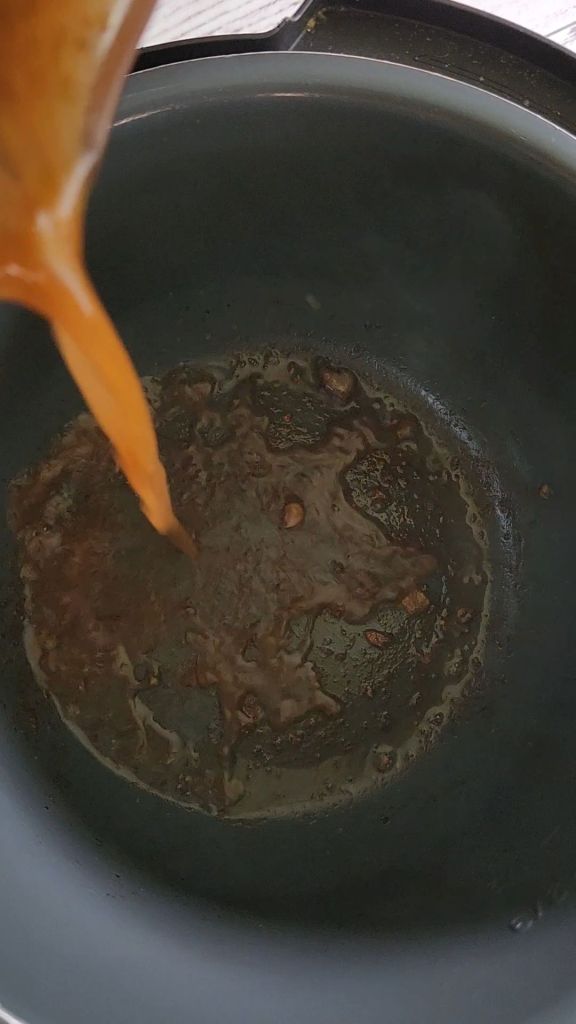 Deglazing the instapot pan with broth for Easy instant pot carnitas from a pork shoulder roast.