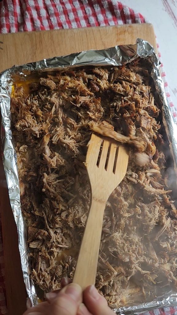Stirring Shredded pork shoulder meat for Easy instant pot carnitas from a pork shoulder roast.