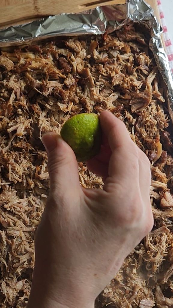 Squeezing fresh lime juice over prepared carnita meat.