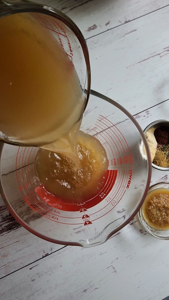 Mixing broth and spices for Easy instant pot carnitas from a pork shoulder roast.