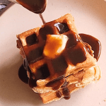 Pouring Maple syrup over Easy gluten free low carb breakfast chaffle waffles batter into waffle maker.