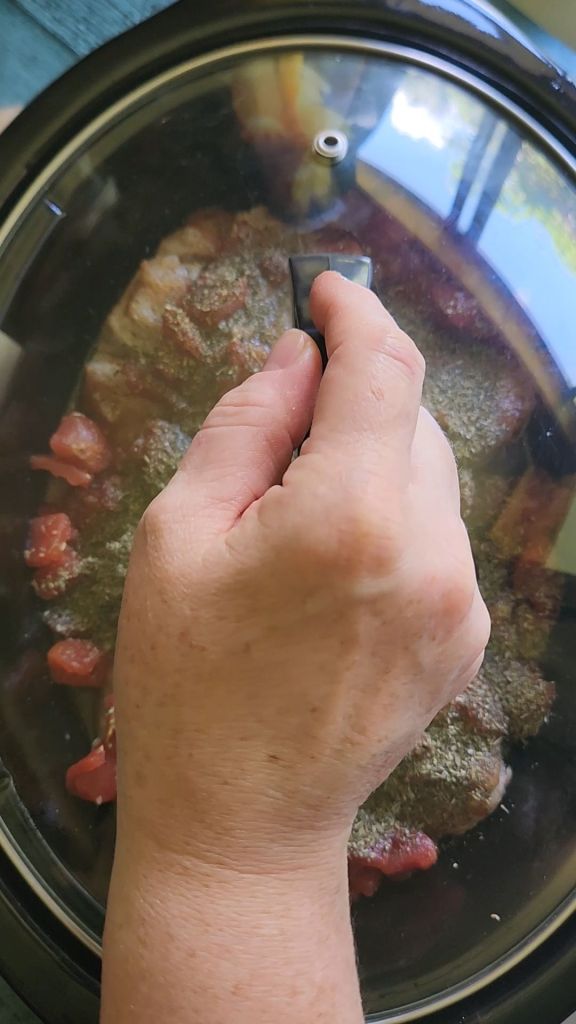 Placing lid on crock pot to cook pork loin roast