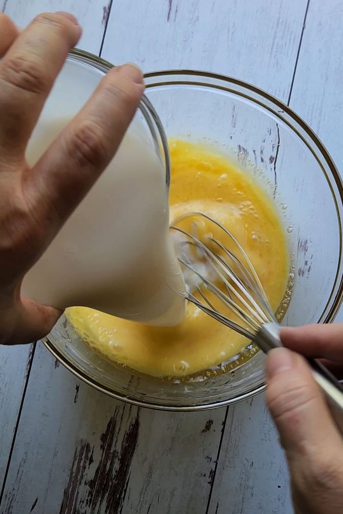 Adding almond milk to wet ingredients.