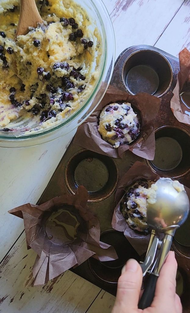 Scooping batter into muffin tin for Quick Gluten Free Blueberry Muffins with a Cake Mix.