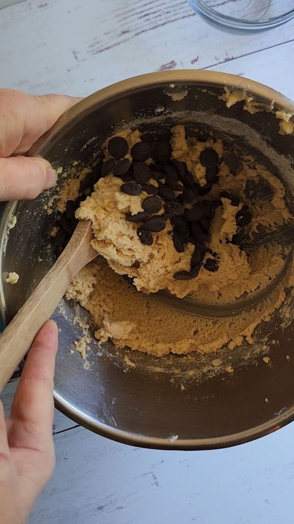 Stirring chocolate chips into batter for Soft batch Gluten Free low carb chocolate chip cookie.