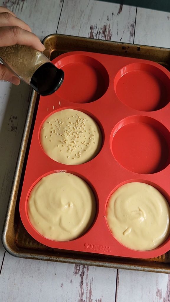 Sprinkling sesame seeds over The best ever gluten free soft hamburger buns batter.