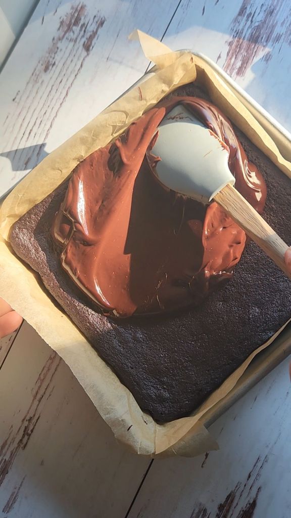 Spreading ganache onto cooled brownies.