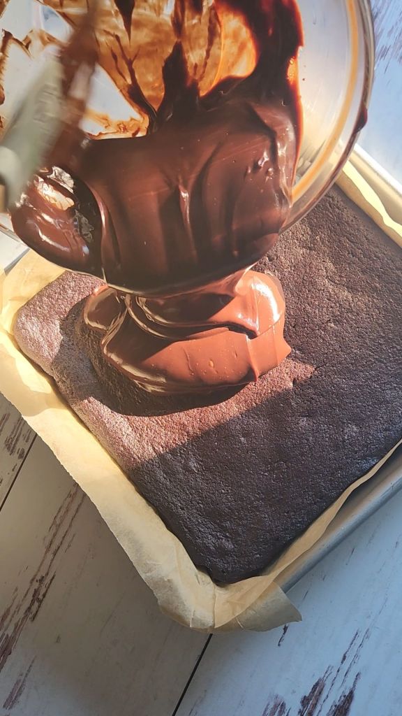 Spreading ganache onto cooled brownies.