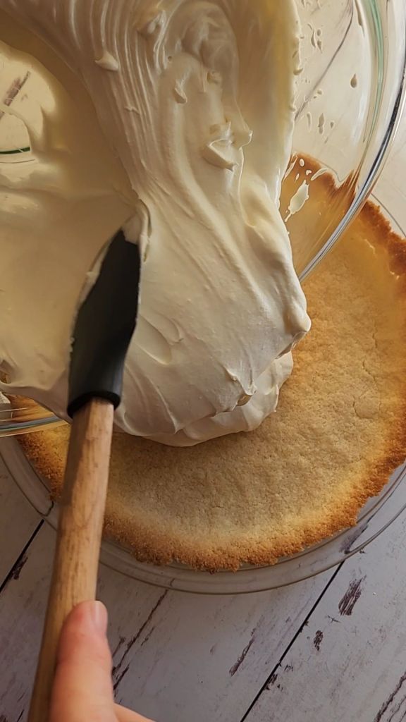 Spreading filling for 5 ingredient No bake gluten free cheesecake into prepared almond flour crust.