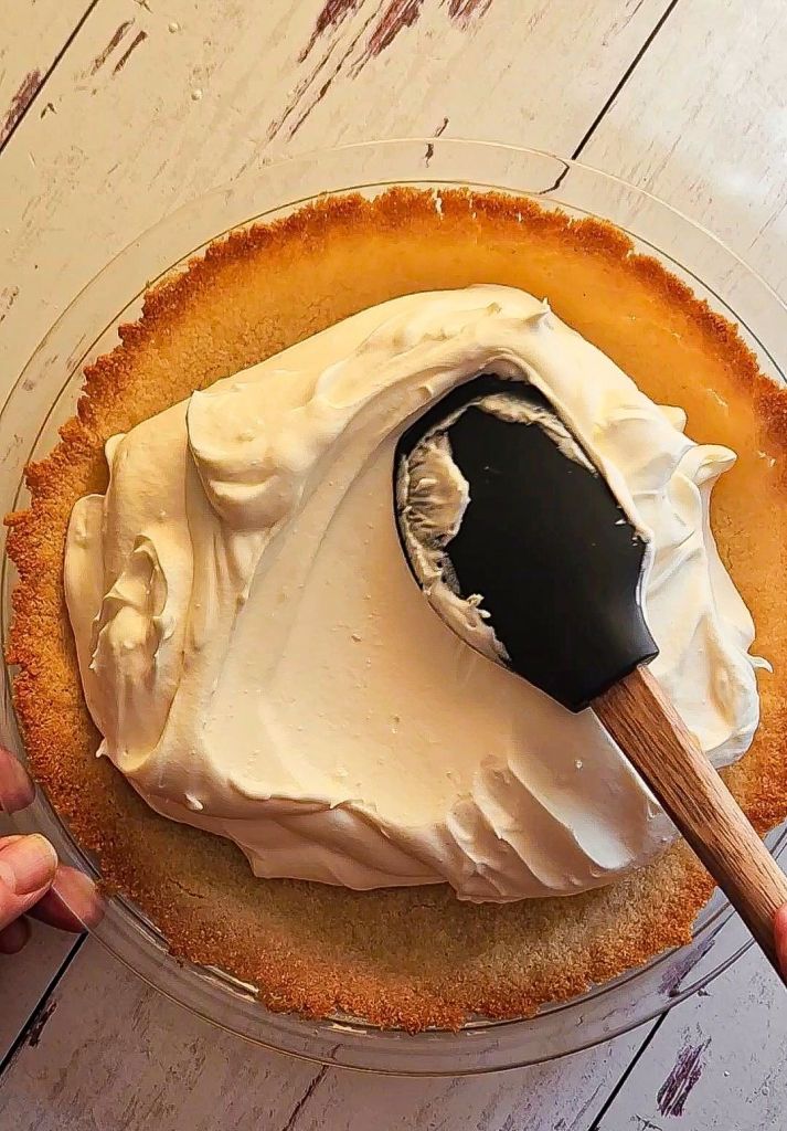 spreading cheesecake filling into baked crust.