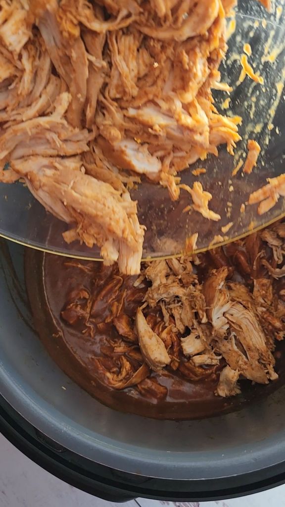 Stirring shredded chicken into the sauce.