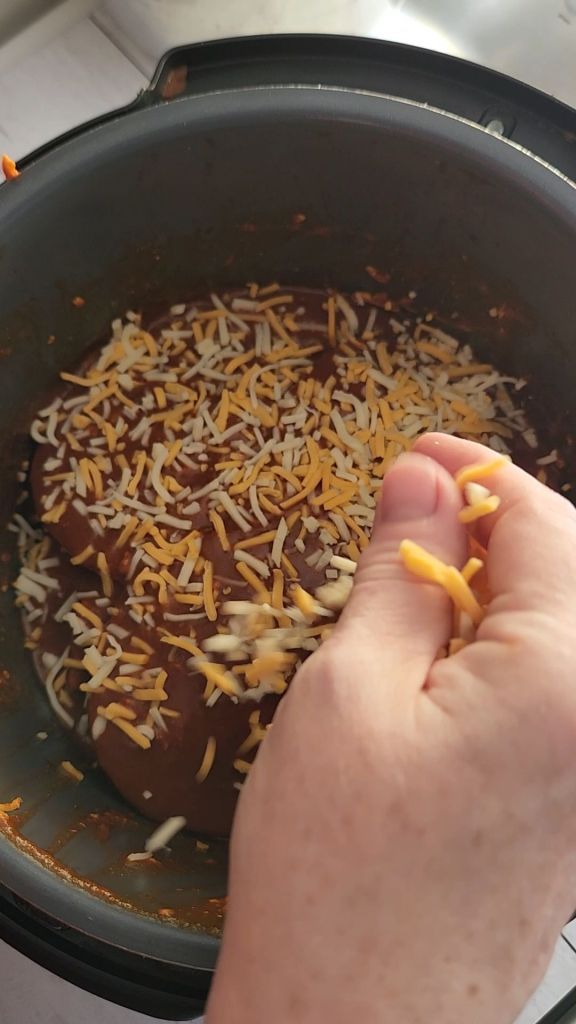 Sprinkling cheese on top of Easy instapot gluten free mexican casserole recipe.