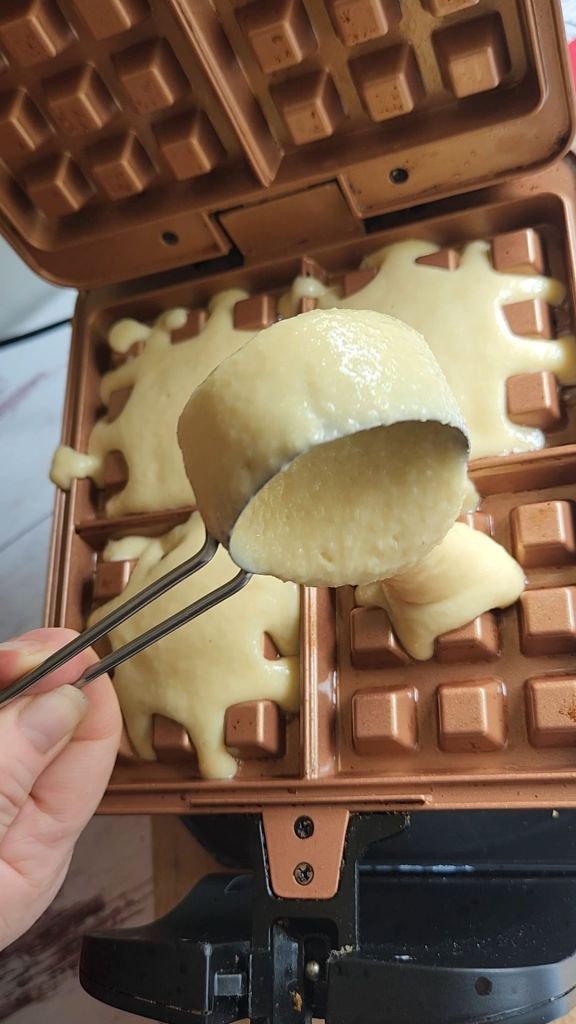 Pouring Easy Gluten-Free Dairy-Free Blueberry Waffle batter into waffle iron.