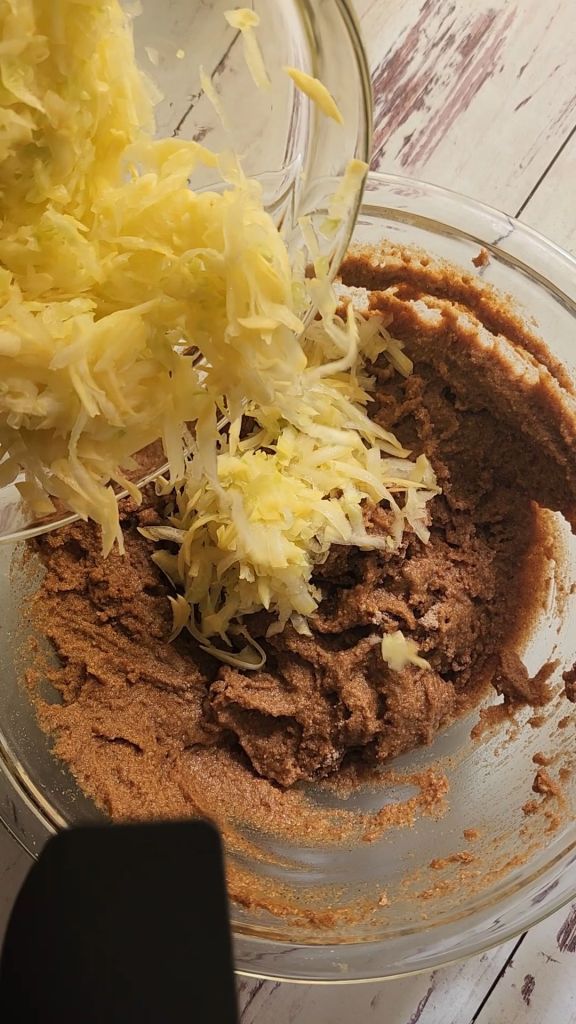 Folding shredded yellow squash into the battery for Easy gluten free zucchini bread with yellow squash recipe.
