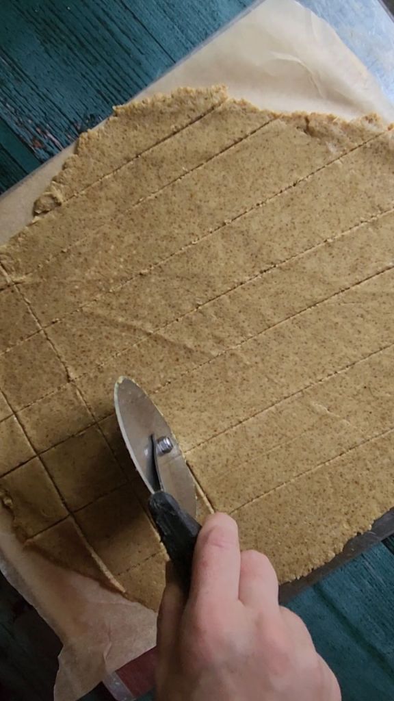 Cutting dough for gluten, free nut.Free sunflower seed crackers with a pizza cutter.