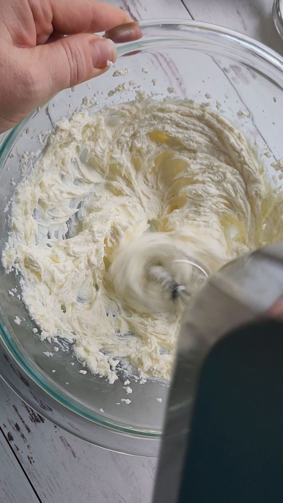Whipping cheesecake batter with an electric mixer.