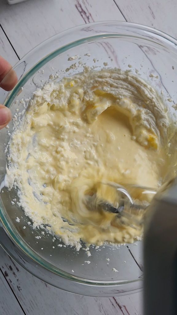 Whipping cheesecake batter with an electric mixer.