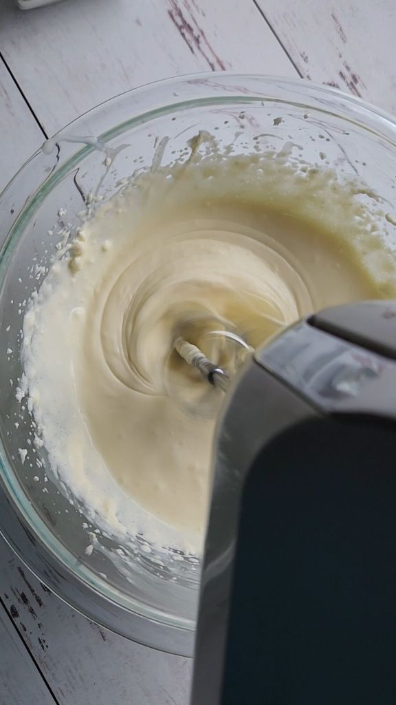 Whipping cheesecake batter with an electric mixer.