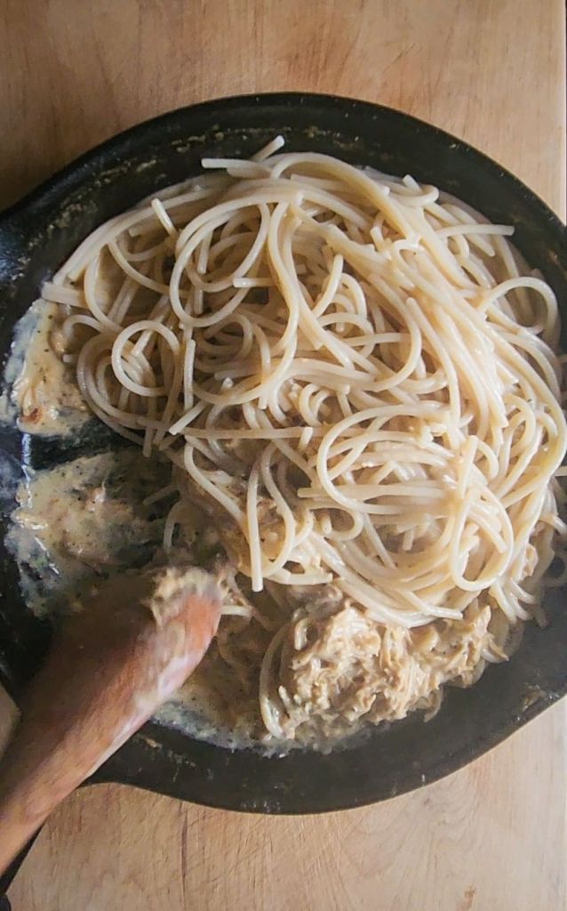 Folding noodles into cream sauce.