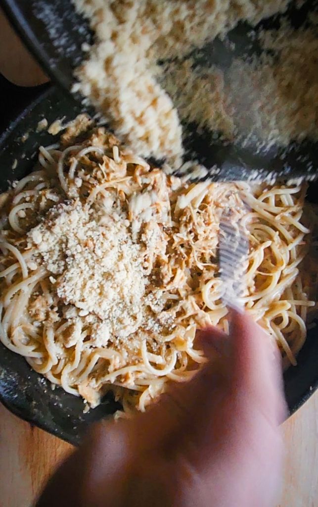 Sprinkling crumbs onto prepared casserole.