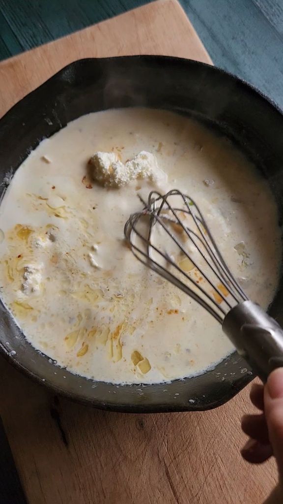 Whisking cream cheese into cream sauce.
