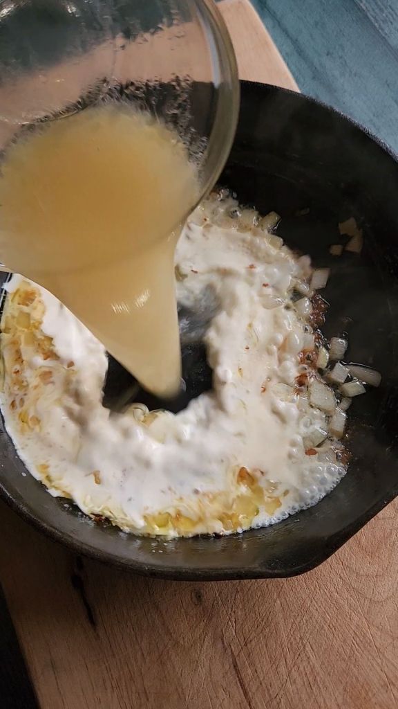 Pouring broth into cream sauce.