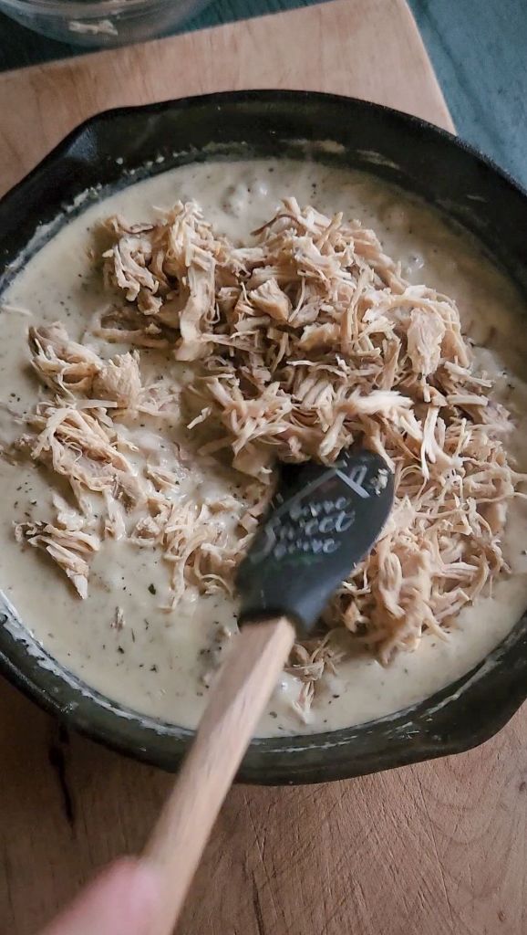 Stirring meat into cream sauce.