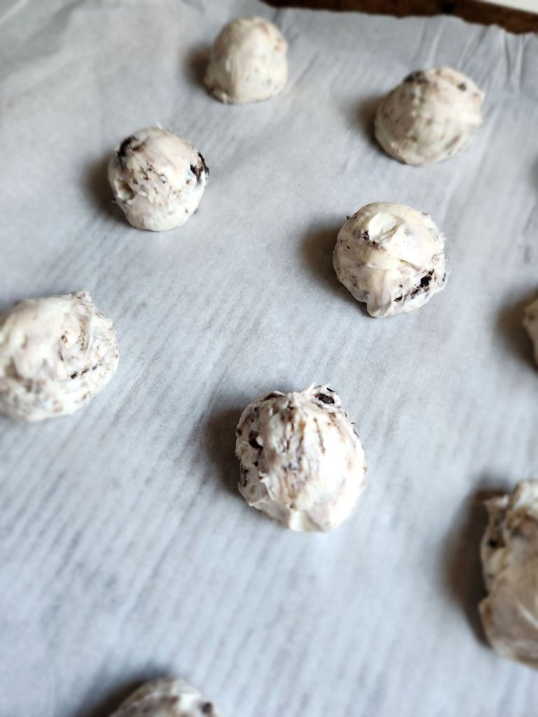 No bake chocolate sandwich cookie cheesecake balls on a parchment lined pan