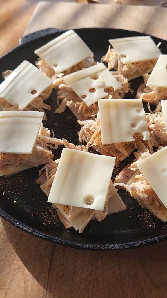 placing swiss cheese on top of shredded chicken.