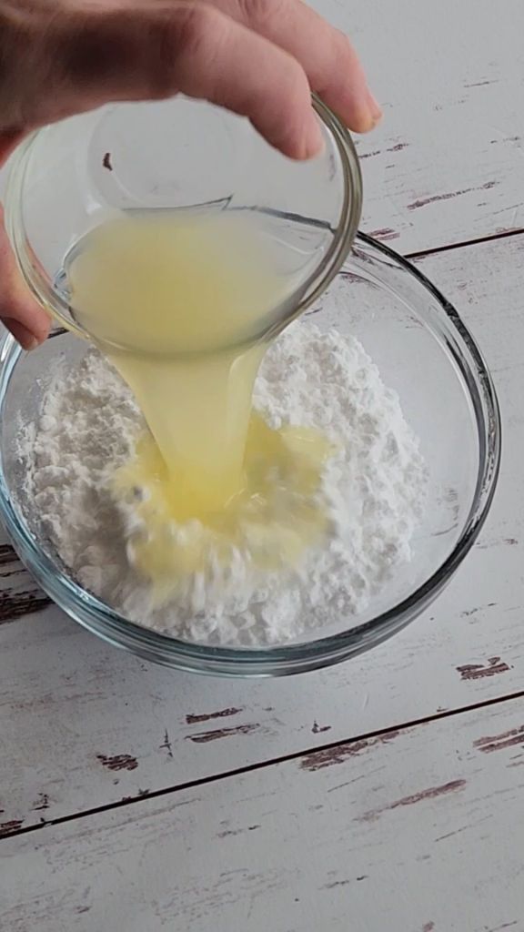 Pouring lemon juice into powdered sugar for lemon glaze